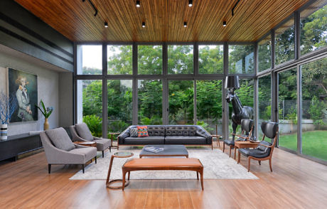 Modern living room with large windows, wooden ceiling, and stylish furniture.