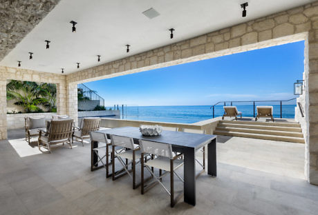 Seaside open patio with dining area and ocean view.