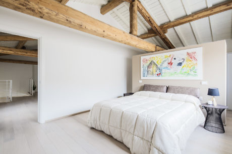 Contemporary bedroom with exposed wooden beams and colorful artwork.