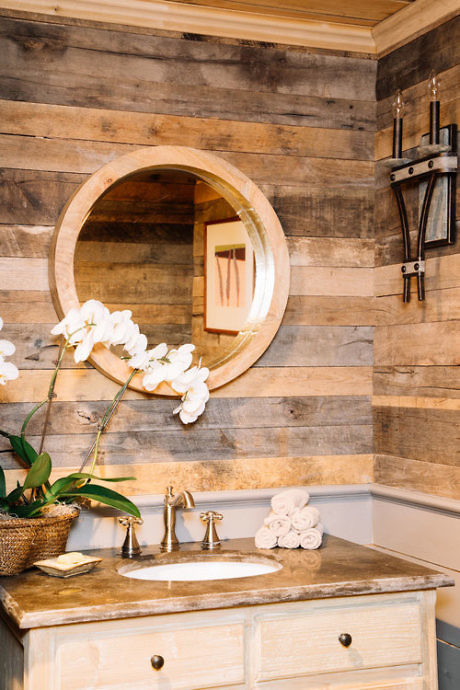 Rustic bathroom with wooden walls, round mirror, and vintage sink.