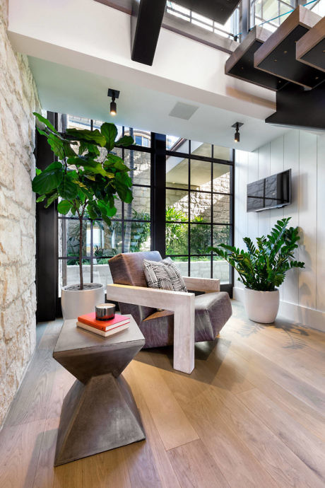 Modern living room with large windows, a couch, plants, and wooden floors.