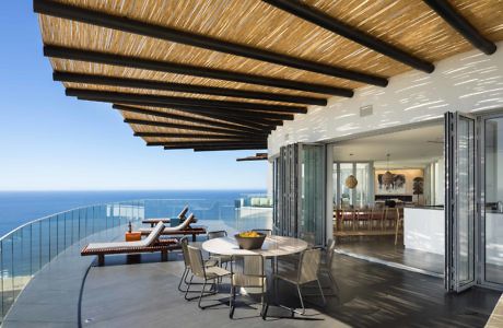 Oceanfront terrace with a slatted wooden overhang and glass balustrades.