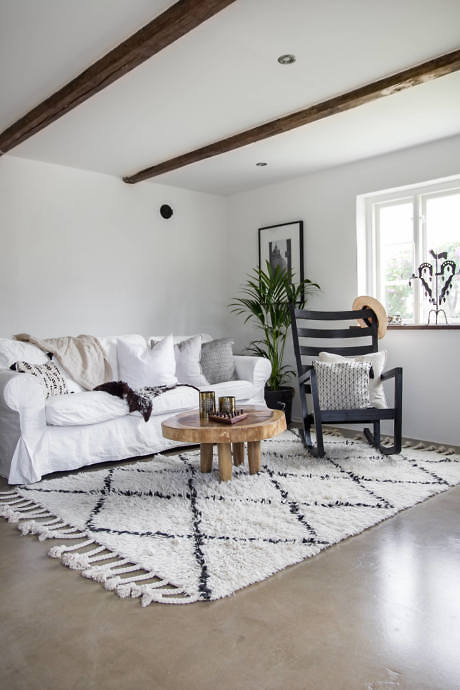 Minimalist living space with neutral tones and exposed wooden beams.