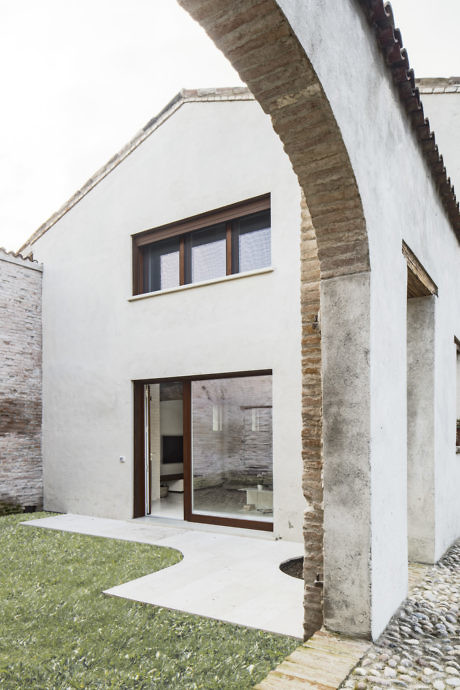 Contemporary white house with arched entryway and large windows.