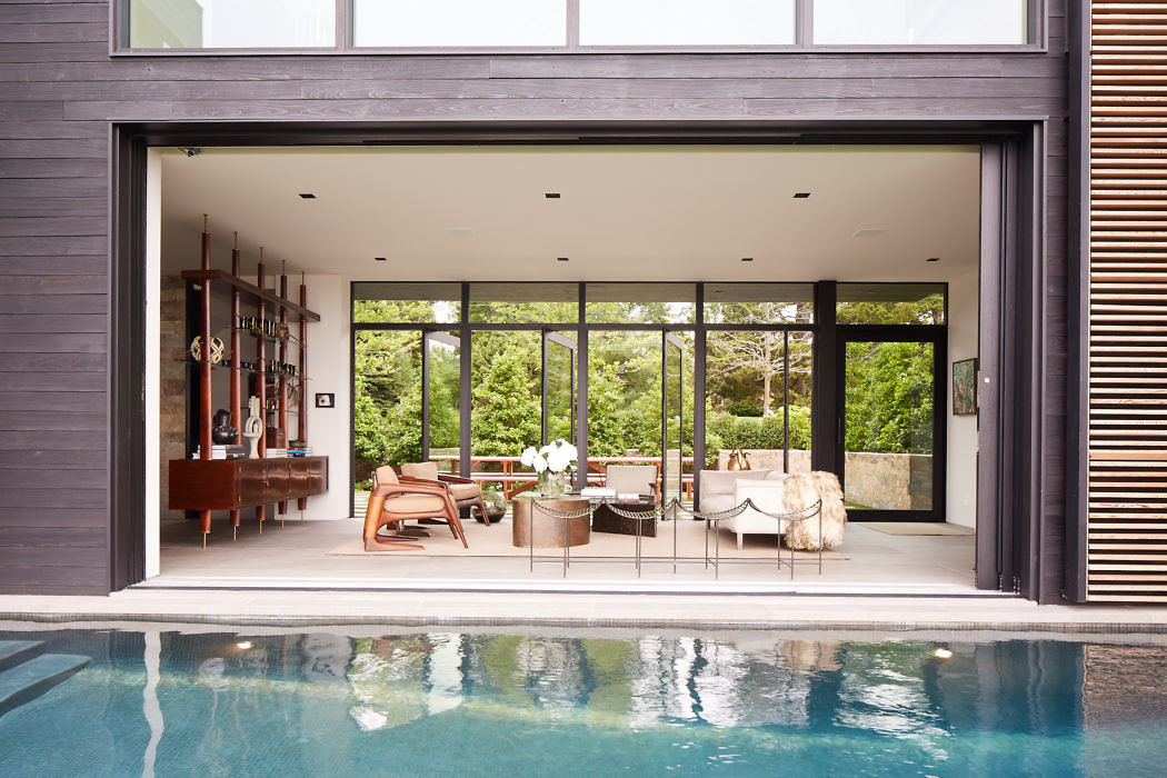 Modern house interior opening onto a pool with sliding doors.