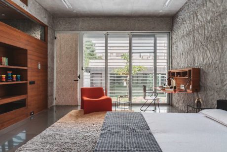 Stylish room with textured walls, large windows, and vibrant armchair.