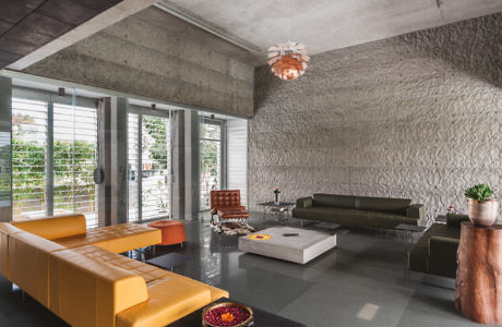 Modern living room with textured walls, concrete ceiling, and colorful furniture.