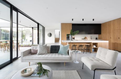 Contemporary living space with wooden kitchen, large windows, and minimalist decor.