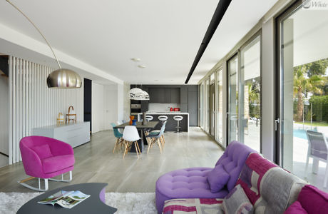 Modern living room with colorful furniture and sliding glass doors leading to a garden.