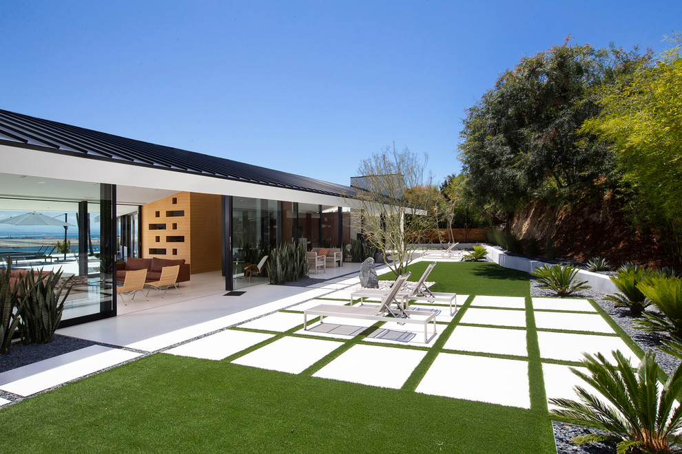 Sleek house with expansive glass walls, green lawn, and geometric walkways