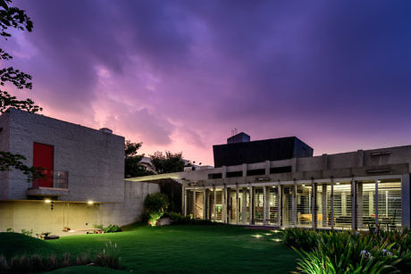 Modern building at dusk with illuminated windows and colorful sky.