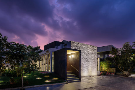 Contemporary house at dusk with artistic facade and illuminated entrance.