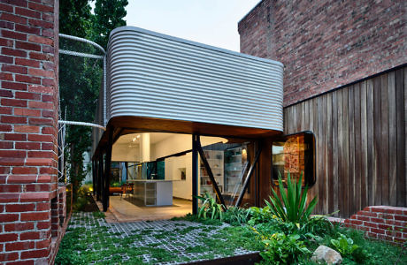 Contemporary curved structure with open ground level and garden.