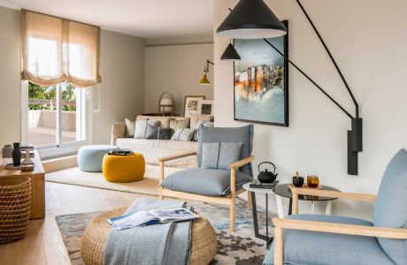 Modern living room with blue and beige decor, wall art, and pendant light.