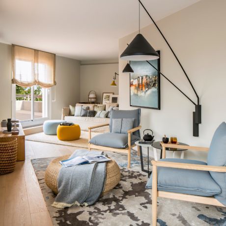 Modern living room with blue and beige decor, wall art, and pendant light.