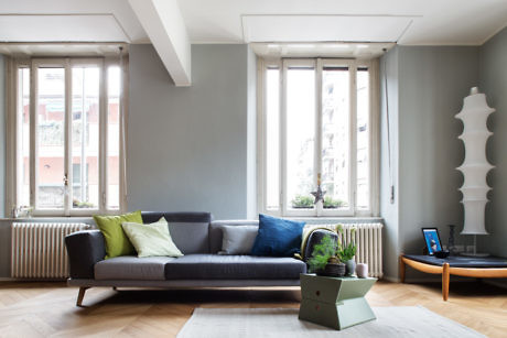 Modern living room with gray walls, large windows, and a comfortable sofa.