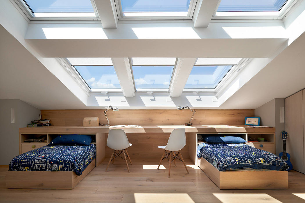 Bright attic bedroom with skylights, twin beds, and a study area.