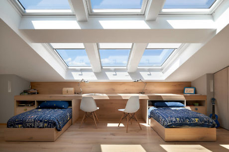 Bright attic bedroom with skylights, twin beds, and a study area.