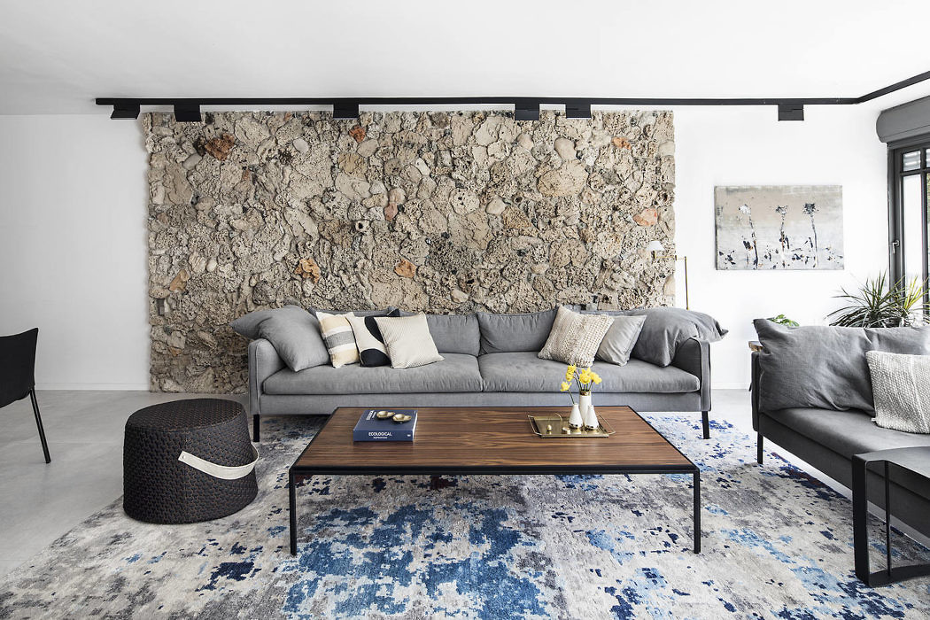 Modern living room with a stone accent wall, sectional sofa, and patterned rug