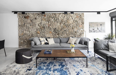 Modern living room with a stone accent wall, sectional sofa, and patterned rug