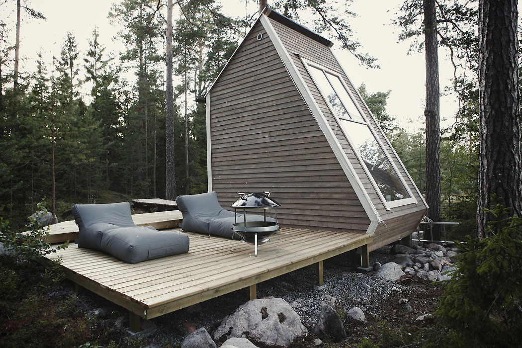 A-frame cabin with large window and wooden deck in a forest setting.