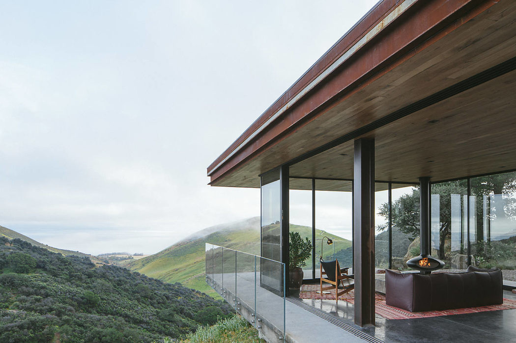 Modern house terrace with a glass facade overlooking green hills.