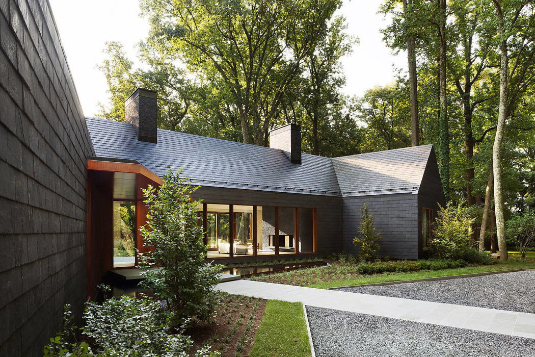 Contemporary house with large windows and dark wood siding in a forest setting.