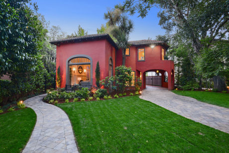 Two-story terracotta villa with arched doorway, surrounded by lush garden and