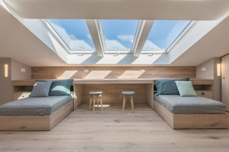 Sleek attic bedroom with skylights and twin beds.