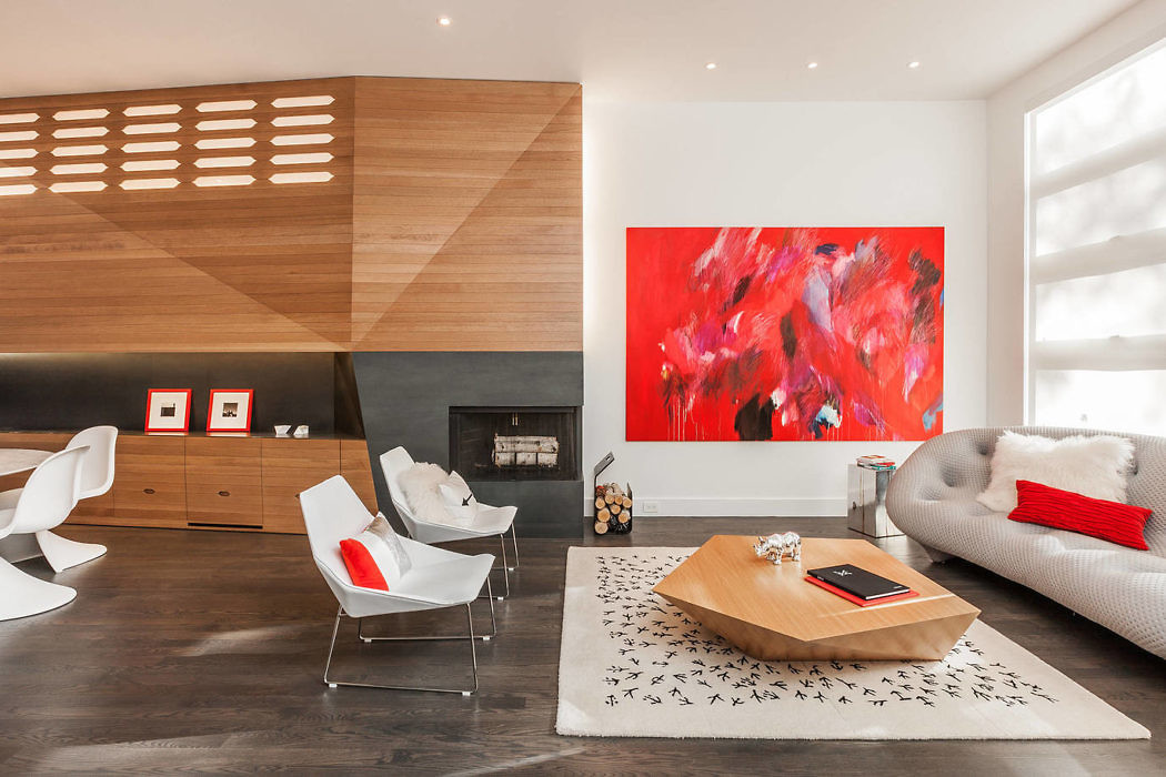 Modern living room with red art, white chairs, a wooden wall, and a
