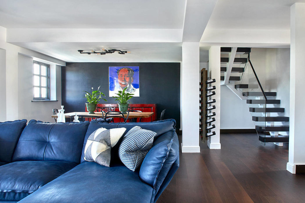 Contemporary living room with dark blue sofa and spiral staircase.