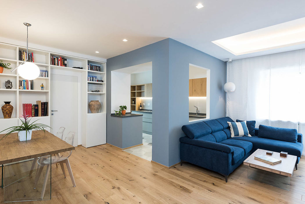 Contemporary open-plan living space with blue accents and wooden floors.