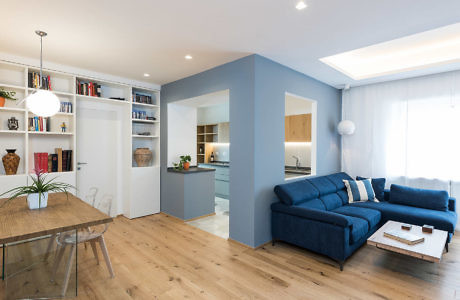 Contemporary open-plan living space with blue accents and wooden floors.