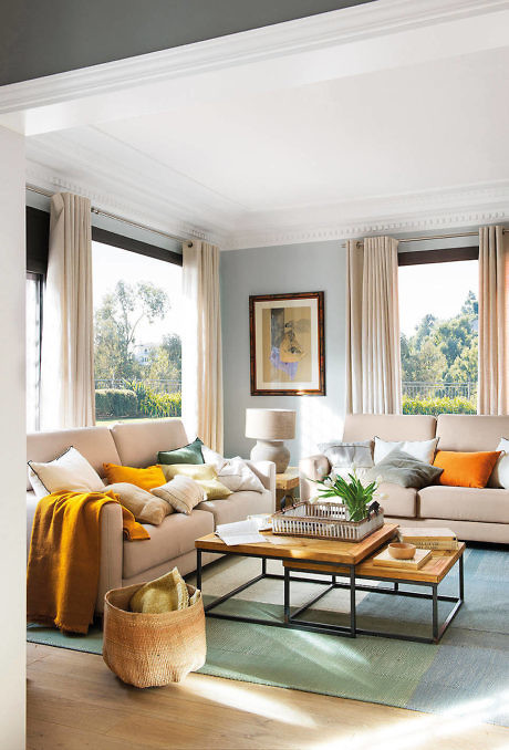 Elegant living room with a beige sofa, large windows, and warm accents.