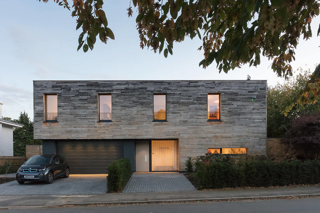 Contemporary house with wood paneling and integrated garage at twilight.