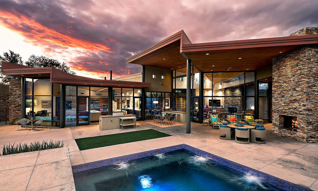 Contemporary house with large windows, pool, and sunset sky