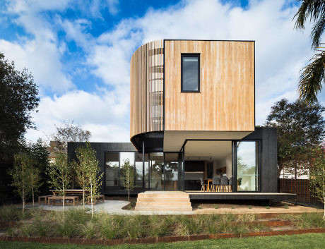 Contemporary house with wooden upper design and expansive glass windows.