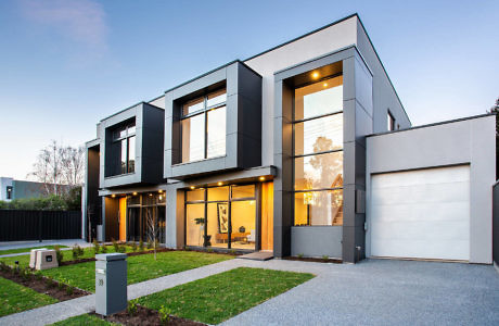 Contemporary two-story house with large windows and a garage at dusk.