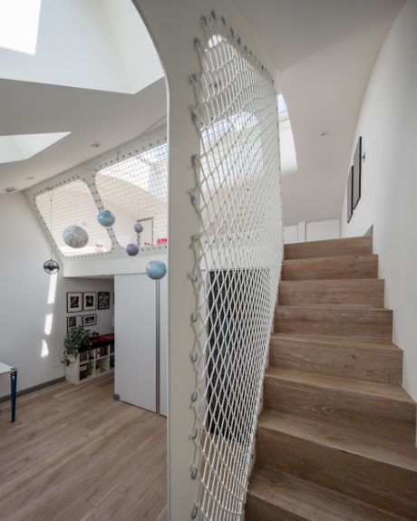 Bright staircase with wooden steps and unique net barrier.