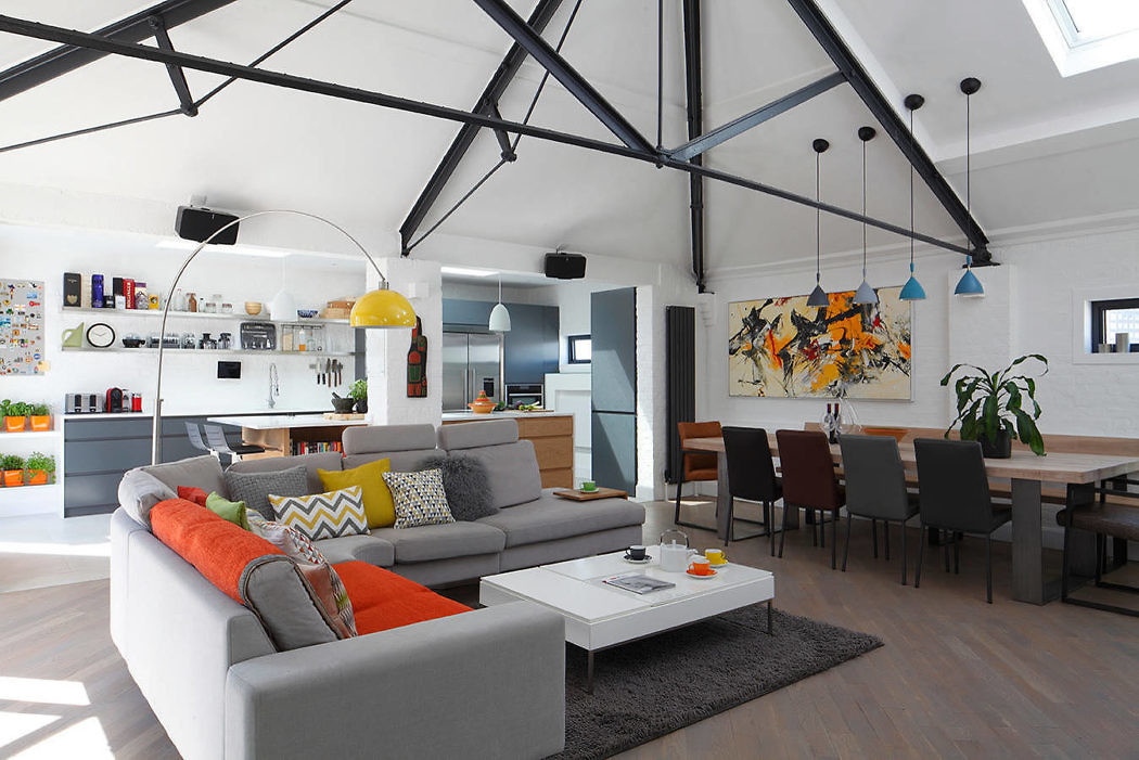 Modern living room with sectional sofa, colorful decor, and open kitchen.