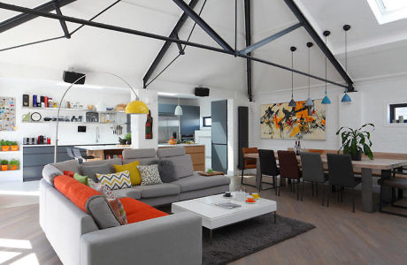 Modern living room with sectional sofa, colorful decor, and open kitchen.