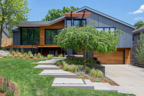 Contemporary house with wood and gray paneling, large windows, and a stone