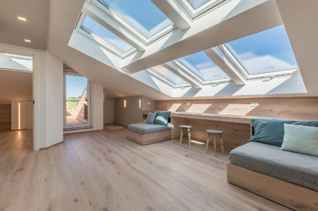 Bright attic room with multiple skylights and wooden floors.