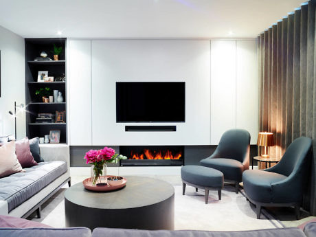 Sleek living room with wall-mounted TV above a fireplace, plush seating,