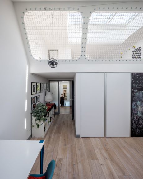 Bright hallway with meshed mezzanine, wood flooring, and wall art.