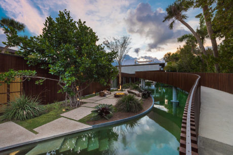 Backyard with curvy pool and wooden fence at dusk.