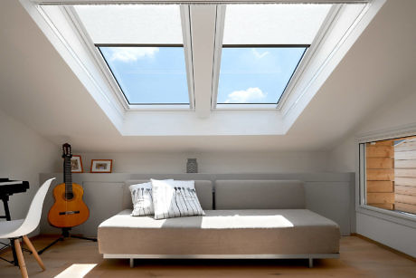 Bright attic bedroom with skylights and a guitar.