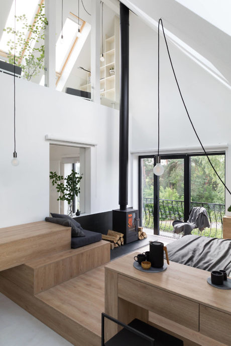 Modern two-level room interior with wooden furniture and large windows.