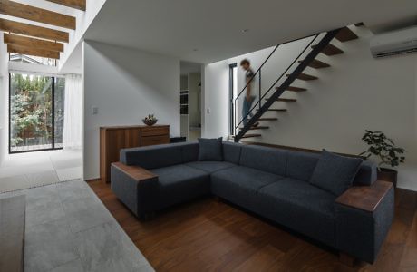 Modern living room with large sectional sofa and floating staircase.