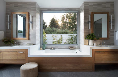 Modern bathroom with wooden cabinets and a large window above the bathtub.